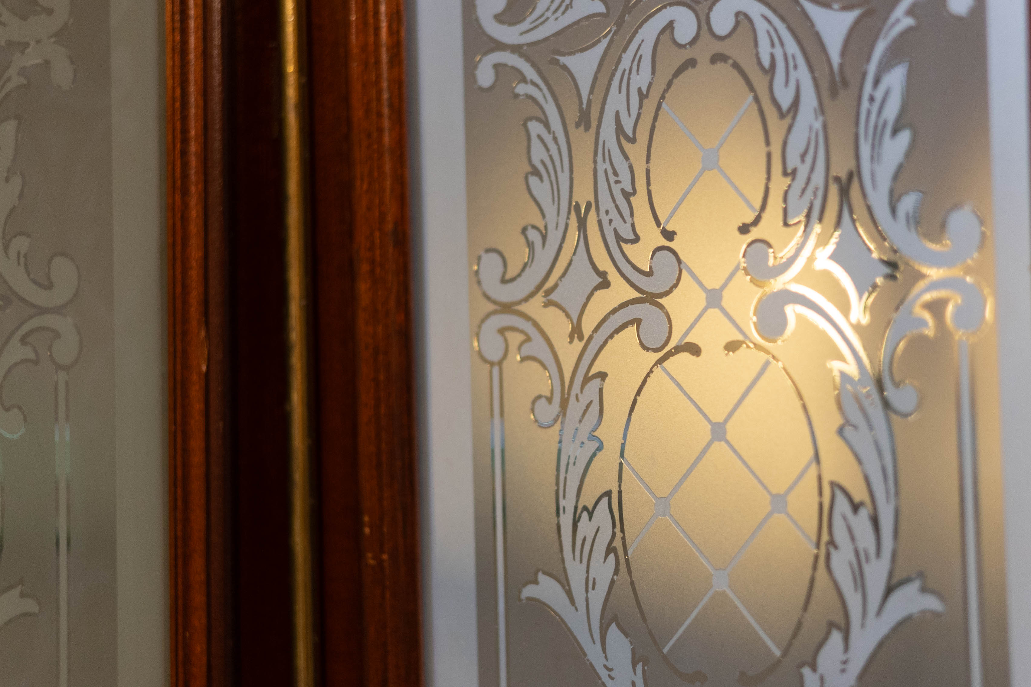 Ornamentales Glas-Intarsienpaneel in einem Wiener Zinshaus — warmes Licht